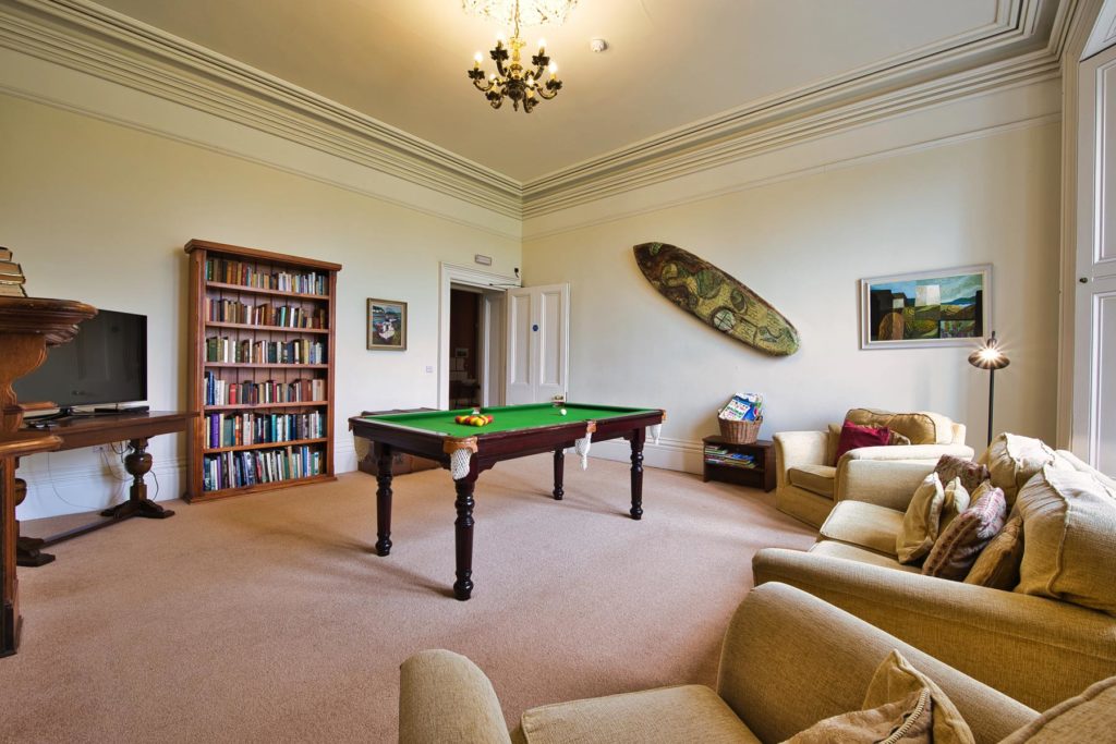 Pool table in large stately room with gold sofas