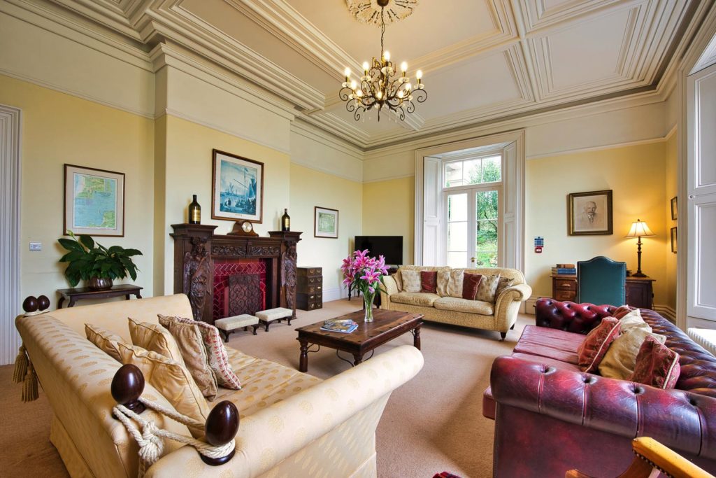 cream and red leather sofas in stately room with ornate fireplace
